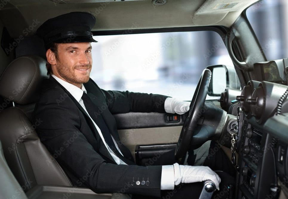 Uniformed Chauffeur Service - St. Louis Executive Transportation A professional uniformed chauffeur wearing a cap and white gloves smiling while driving a luxury vehicle, representing Gateway Limousine's premium drive-as-directed and executive car services in St. Louis.