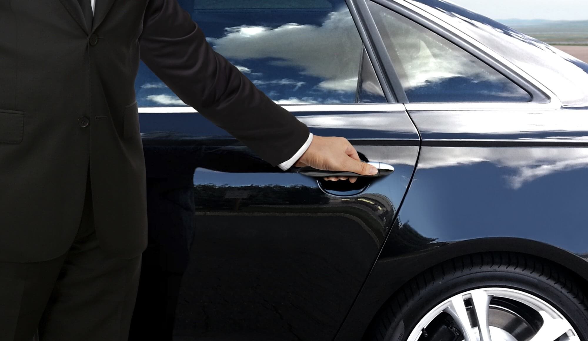 St. Louis Airport Limo Service - Chauffeur Opening Door A professional chauffeur in a black suit opening the rear door of a luxury black car for a passenger arriving at St. Louis Lambert International Airport (STL).